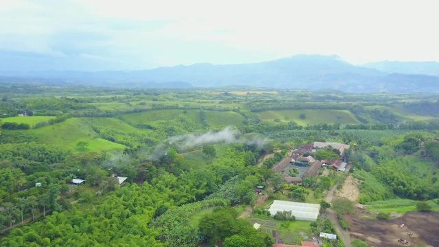 AERIAL: rotating around some fire smoke in the precious Panaca park in Quidio, Colombia, that's been surrounded by coffee plantations.