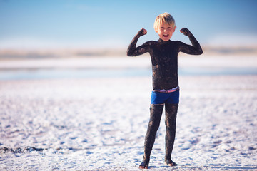 young boy smeared with natural mineral mud at the salt lake
