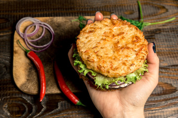 Fototapeta na wymiar Healthy lifestyle, proper nutrition. Healthy rice burger with vegetables, herbs and cutlet in female hands