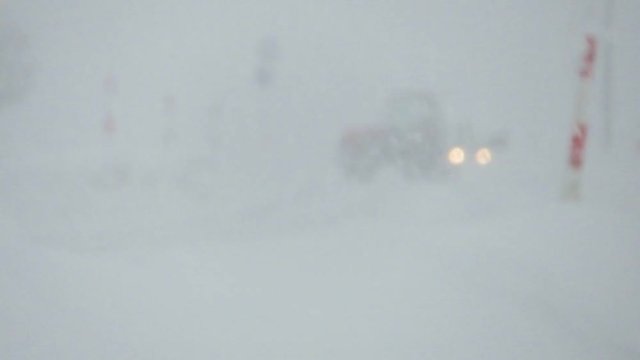 大雪が降る中を走行する自動車　冬　交通　イメージ