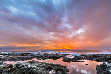 Sunset at Anzota Caves seafront walk. The rays of light coming from the sun illuminating the clouds...