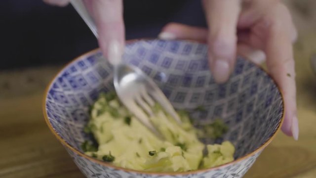 Closeup of a chef making garlic herb butter in a bowl.