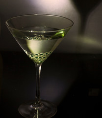glass of martini with a green necklace in it