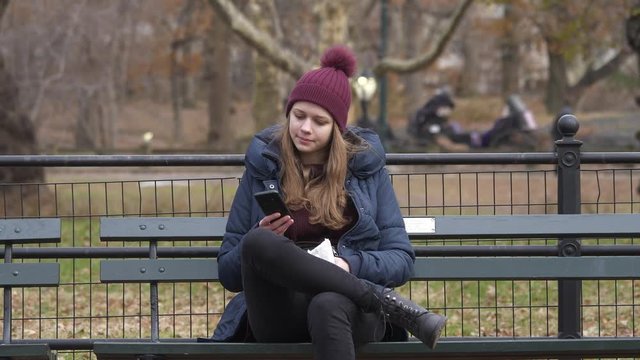 Young woman sits on a bench in Central Park New York