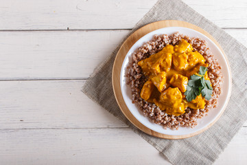 Buckwheat with chicken curry sauce with cashew on white wooden background.