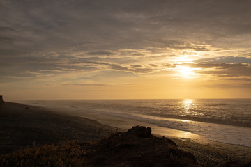 The sun rises over the ocean and disappears into the cloudy sky at Dorie, Canterbury, New Zealand