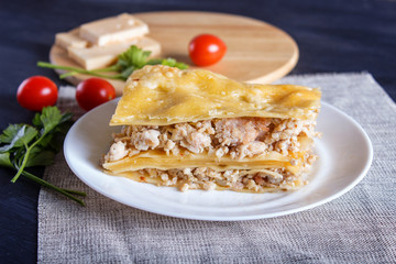 Lasagna with minced meat and cheese on black wooden background.