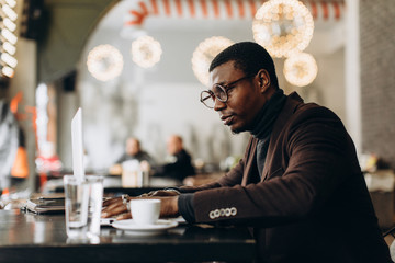Portrait of happy african businessman working on laptop in a restaurant.