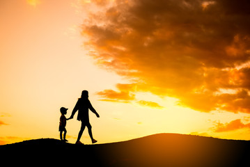 Fototapeta premium Silhouette mother and daughter on the mound at the sky sunset.