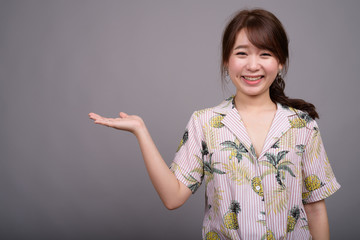 Portrait of young beautiful Asian woman showing copyspace