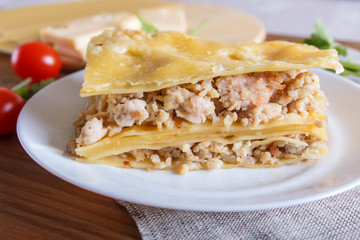 Lasagna with minced meat and cheese on brown wooden background.