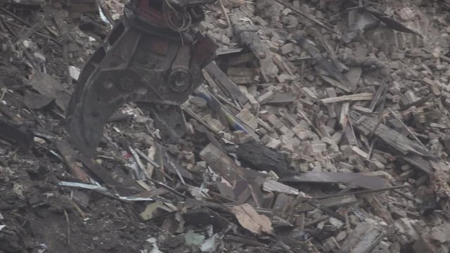 Tearing down and demolishing a beautiful burnt down building with heavy machinery, bulldozers and cranes. Tracking shot.