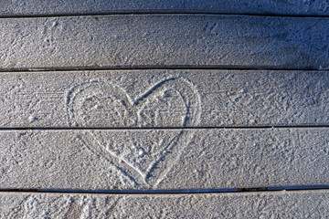 Snow on wooden table, love heart symbol