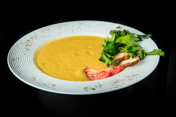 yellow cream soup decorated with mushrooms, tomatoes, and parsley