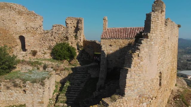 Detail of the side of a church of the Palafolls Castle ruins on the top of the hill on a beautiful sunny day. Catalonia Spain. Aerial view travelling