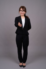 Obraz na płótnie Canvas Full length portrait of young Asian businesswoman standing