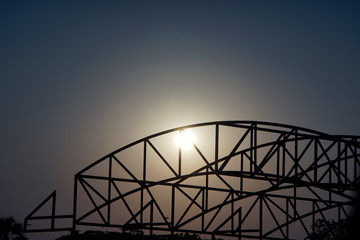 Curved metal beam silhouette with sunset sun in background