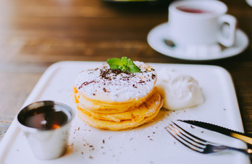 Pumpkin pancakes with maple syrup, chocolate  and sour cream on a plate. Wooden table. Autumnal breakfast idea.