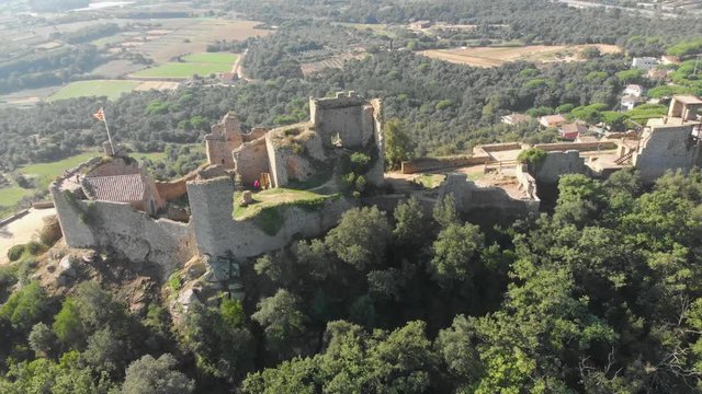 Landscape of the ruins of Palafolls Castle on a beautiful sunny day with the Catalonia flag fluttering. Catalonia Spain. Aerial view travelling orbit