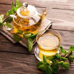 A cup of fresh hot tea with mint on a dark wooden background. The concept of healthy eating. Copy...
