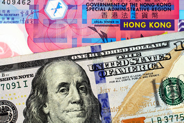 A macro image of a ten Hong Kong dollar bill with a blue American one hundred dollar bill