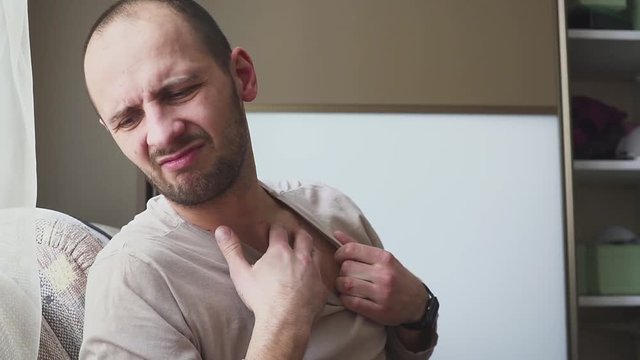 Allergies to the neck and shoulders. Man with psoriasis is touching his dry, itchy, and scaly skin on neck.