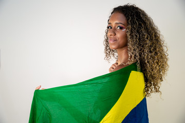 Happy black woman fan holding a Brazilian flag. Brazil colors in background, green, blue and yellow. Elections, soccer or politics.