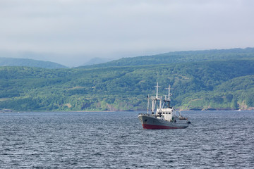 Fishing boat sailing on the background of the island of Iturup