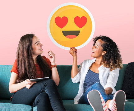 Cheerful women holding a heart eyes emoticon icon