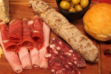 Food tray with delicious salami, pieces of sliced ham and chesses