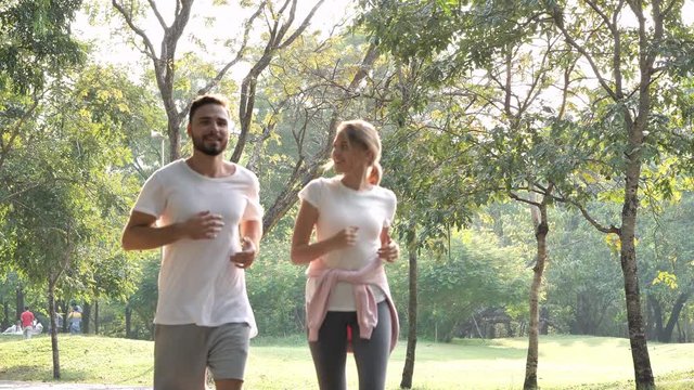 Young Couple jogging and running outdoors in a park on a sunny day.  healthy life, lifestyle concept. Slow Motion