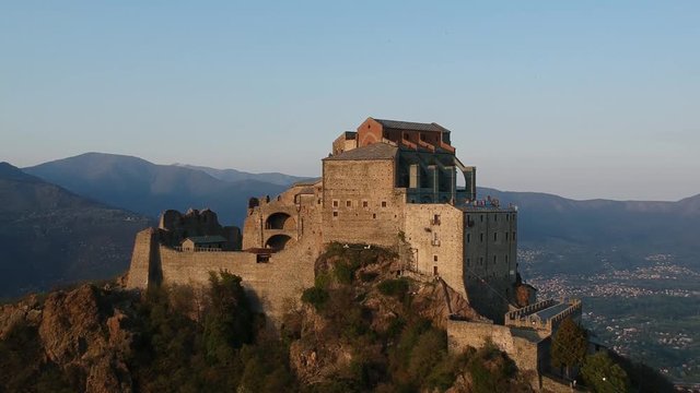 The Sacra di San Michele (Saint Michael's) Abbey, Turin, Italy, sunset shot aerial with mountains of Susa valley in background. Aerial view