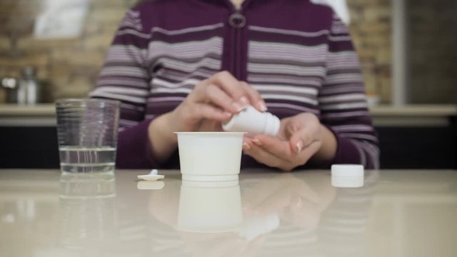 Woman drinking medicine bofore eating yoghurt. Strict medical diet.