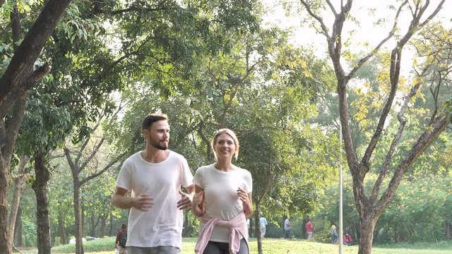 Young Couple jogging and running outdoors in a park on a sunny day.  healthy life, lifestyle concept. Slow Motion