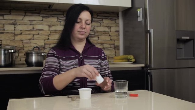 Woman drinking medicine bofore eating yoghurt. Strict medical diet.