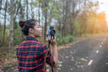 Beautiful woman with retro camera on the street in the forest alone.
