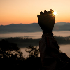 Faith of christian concept: Spiritual prayer hands over sun shine with blurred beautiful sunset background