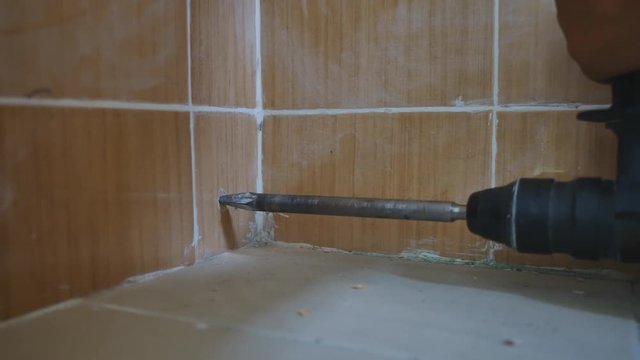 Hand close up of a man to drilling concrete and tighten screw for install water pipe in kitchen room