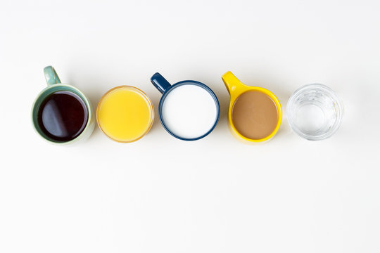 Coffee tea and other drinks in colorful cups on a white background, top view