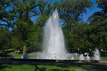 Obraz premium Water fountain with some people around on sunny Sunday afternoon