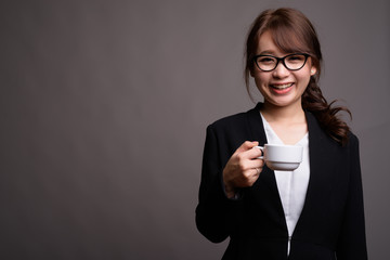 Young beautiful Asian businesswoman holding coffee cup