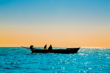 Obraz premium Single fishing boat silhoutte in sea, single fishing boat silhoutte in blue sea with sky