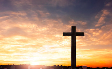 Concept of Jesus Christ: white cross on sunset sky background