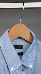 Mens blue button up shirt hanging in closet, denim