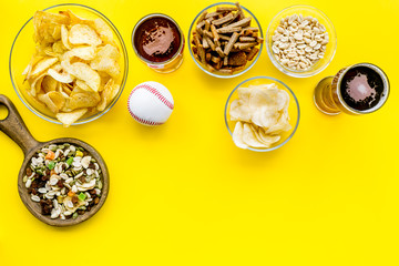 Fast food for TV watching. Snacks on desk.  Chips, nuts, rusks and beer on yellow background top view copy space