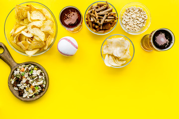 Fast food for TV watching. Snacks on desk.  Chips, nuts, rusks and beer on yellow background top...