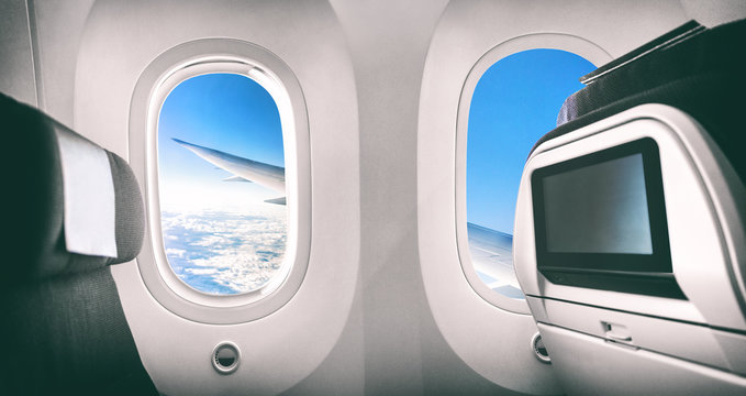 Fototapeta Airplane passenger seat plane interior with window view of flying aircraft wing and movie screen.