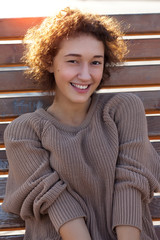 Curly cheerful girl in a knitted sweater