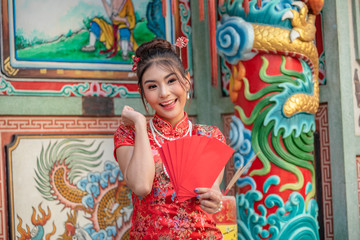 Asian girl in red dress standing in holy place on Chinese New Year.