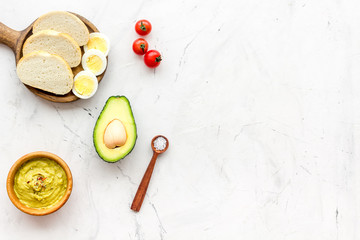 Sandwiches with avocado concept. Whole grain bread, half of avocado, guacamole on white background top view space for text